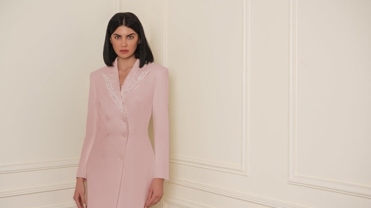 Woman wearing a pink dress against a white wall
